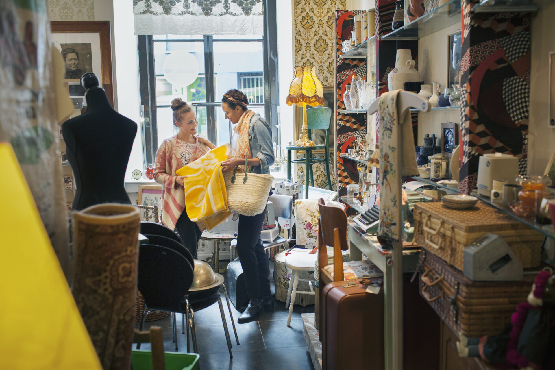 Young Female Customer Looking At Yellow Blanket In Vintage Shop